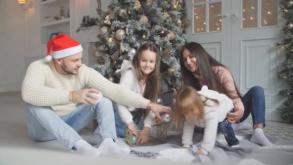 Parent and Two Little Children Having Fun and Playing Together Near Christmas Tree Indoors