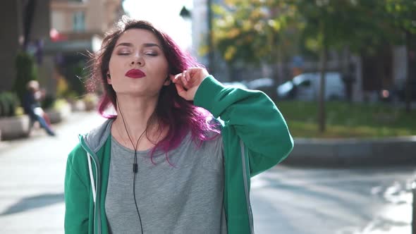 Attractive Young Fashionable Woman with Colored Hair Listening To Music in Earphone and Posing alt
