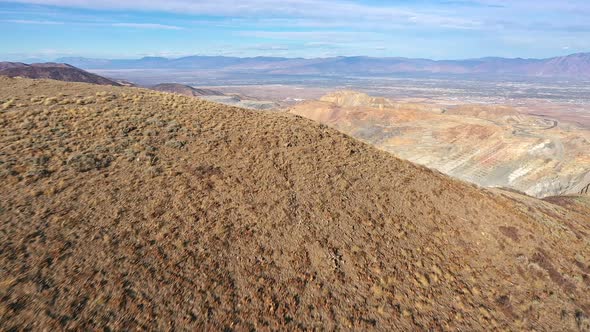 Flying over mountain top revealing Bingham Copper Mine in Utah alt