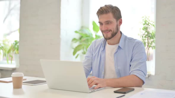 Successful Young Creative Man Celebrating on Laptop in Modern Office alt