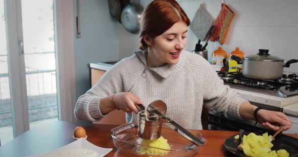 Girl is Mashing Boiled Potatoes for the Preparation of Dumplings and Croquettes alt