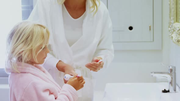 Mother teaching her daughter to brush her teeth in bathroom at home 4k alt