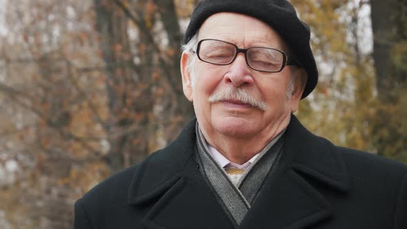 Portrait of old senior Wearing in a black hat and coat and Exhaling Fresh Air, Taking Deep Breath, R alt