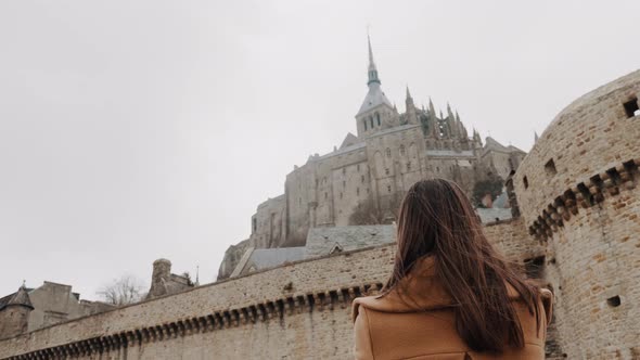 Low Angle Rear View, Beautiful Happy Tourist Woman Stunned By Incredible Mont Saint Michel Castle alt