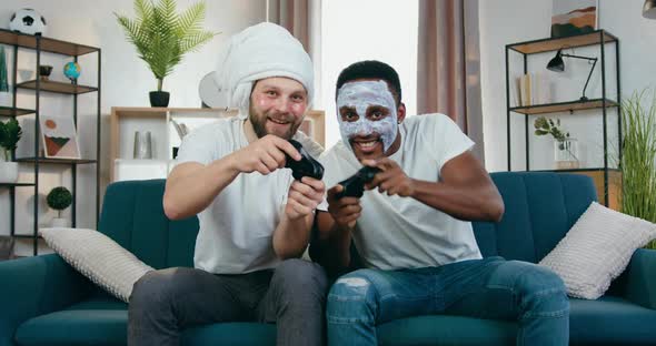 Multiracial Mates with Facial Cosmetic Procedures Sitting on the Couch and Playing Video Games alt