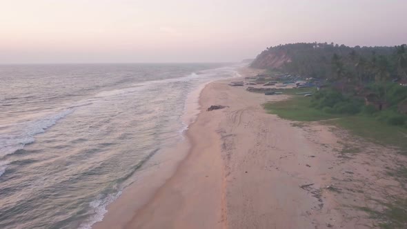 Aerial view of Varkala coastline with waves crashing on the sandy beach, in Kerala, India, at dusk alt