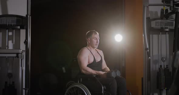 Wheelchair person holding dumbbells and resting during rehabilitation workouts.