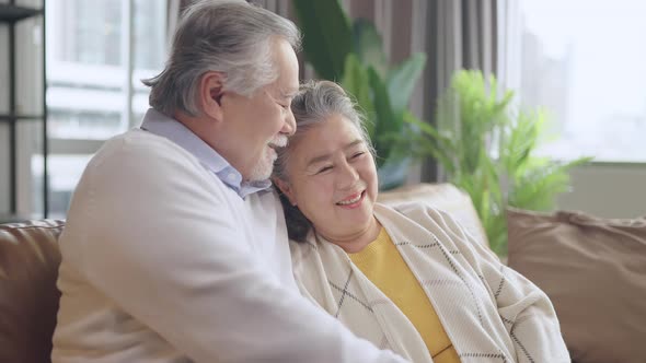 old senior asian retired couple enjoy talking conversation together on sofa