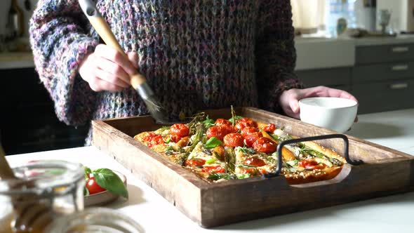 woman prepares focaccia with whole carrots and asparagus alt