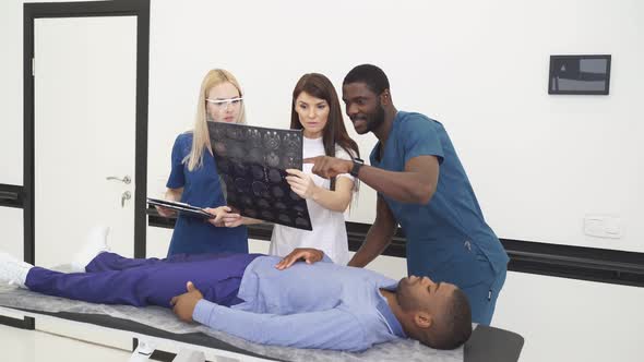 Multiethnic Team of Doctors Performing Emergency Help to Patient Lying Unconscious on Couch
