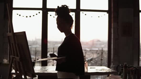 Young Sweet Female Artist Dancing While Drawing Her Picture with Paint Palette in Her Hands in the alt