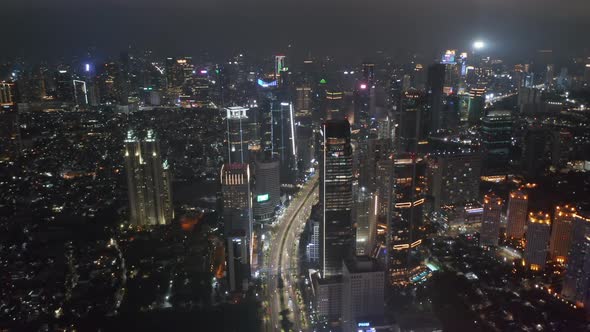 Descending Aerial Pedestal Shot of Night Time Highway Traffic Through Busy Modern City Center in alt