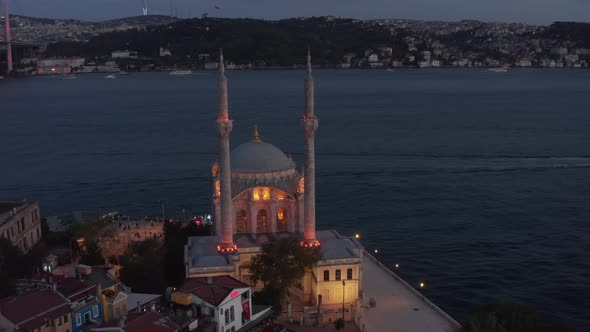 Ortakoy Mosque Illuminated in Beautiful Yellow Light on Water Side at Dusk with Bosphorus and Bridge alt
