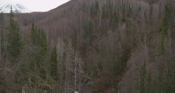 Aerial helicopter tracking across mountaintop towards distant city, drone footage alt