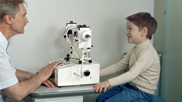 Ophthalmologist in exam room with little boy sitting in