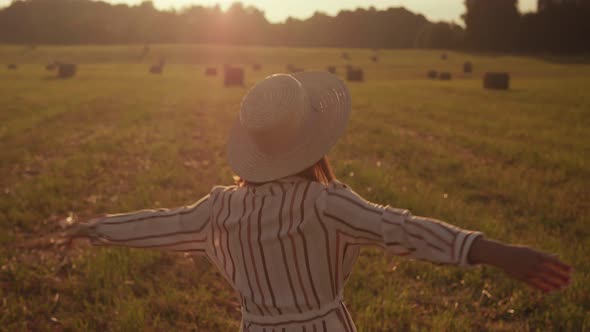 Young woman spinning on a field against a sunset background