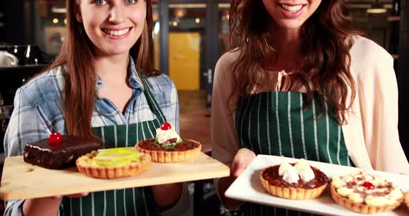 Smiling waitresses showing cakes 4k alt