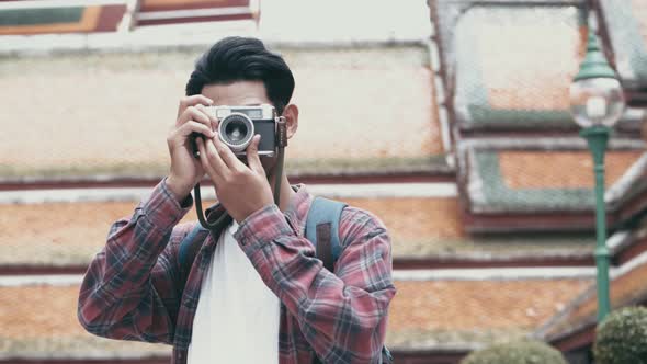 Attractive young Asian man tourists walking traveling and using film camera taking a photo in temple