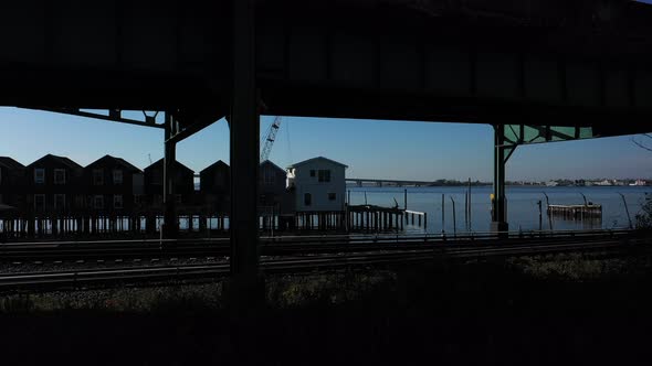 A drone shot in front of elevated train tracks near a bay in Queens, NY. The camera boom up to the t alt