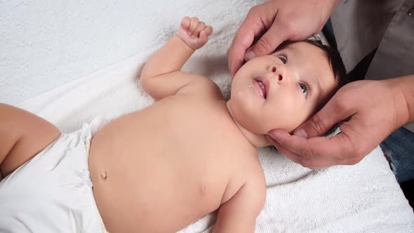 The Masseur Gives a Massage To the Baby. A Child Who Is Being Massaged Is Lying on the Couch