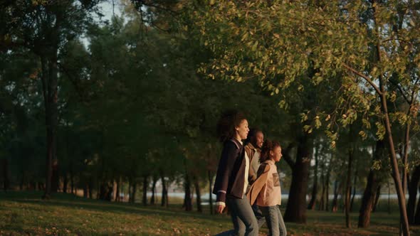 Family Walking Autumn Park Holding Hands Together in Evening Golden Sunlight alt