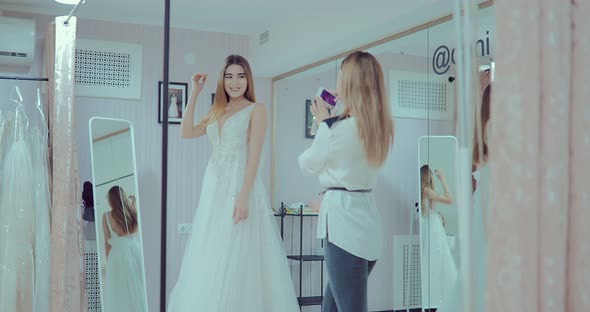 Beautiful Girl Makes the Fitting of a Luxurious Wedding Dress in Front of a Mirror alt