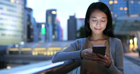 Woman looking at mobile phone in the city at night  alt