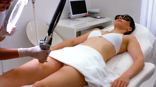 Doctor performing laser hair removal on patient skin alt