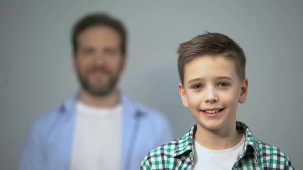 Boy Smiling at Camera, Father Standing on Background, Family Care and Support alt