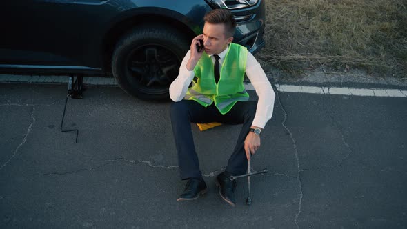 Top View of a Man in a Green Safety Vest Talking on Cell Phone alt