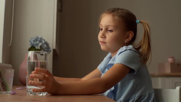 Closeup Side View of Thirsty Little Girl Writing in Exercise Book Taking a Break and Drinking Fresh alt