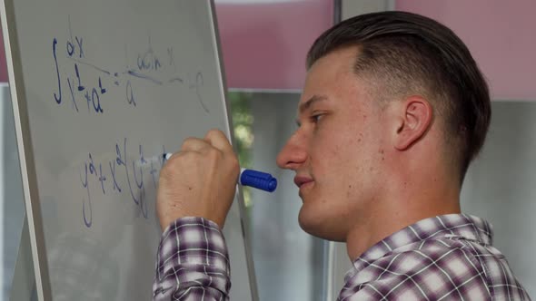 Young Man Solving Math Problem on Whiteboard alt