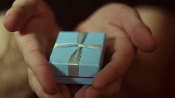 Man Holds Out a Gift in a Blue Box alt