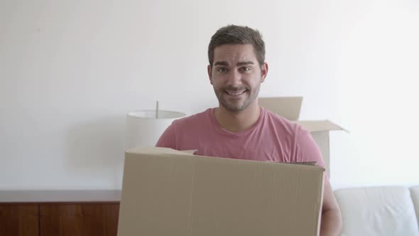 Portrait of Happy Young Man Holding Cardboard Box and Posing alt