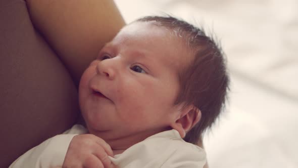 Newborn baby boy and his mother at home. Close-up portrait of the infant alt