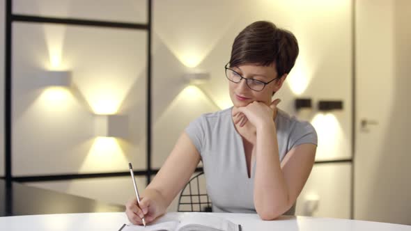 Woman Writing Business Ideas in Notepad alt