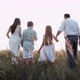 Rear View of Friendly Family Holding Hands and Walking Across Field with Dog - VideoHive Item for Sale