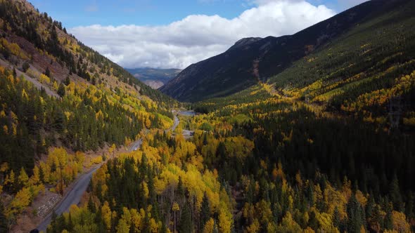 Flying over golden aspens along road through mountain pass in Colorado, Aerial alt