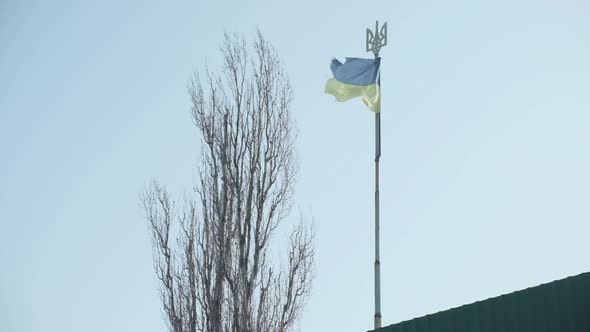 Shabby Blue and Yellow Ukrainian Flag on a Long Pole with a Trident