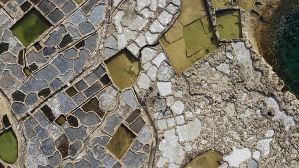 Ascending aerial drone shot of the 300-year-old Salt Pans on the island of Gozo in Malta. alt