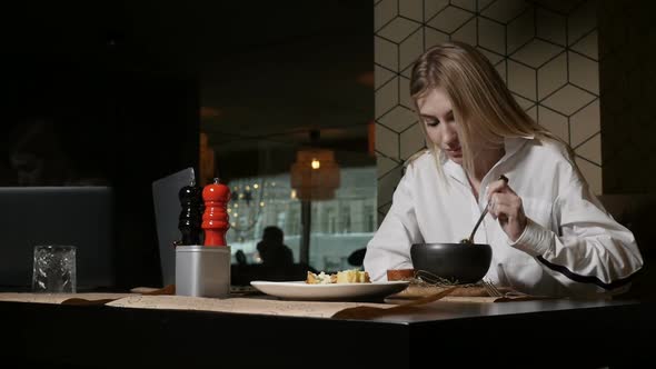 a Young Blonde Woman Eating Soup Sitting in a Restaurant