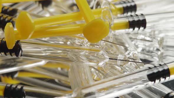 Close-up disposable syringes rotate against an unspecified background.