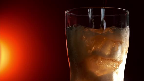 Pouring Red Soft Drink Into a Glass Against Red Background