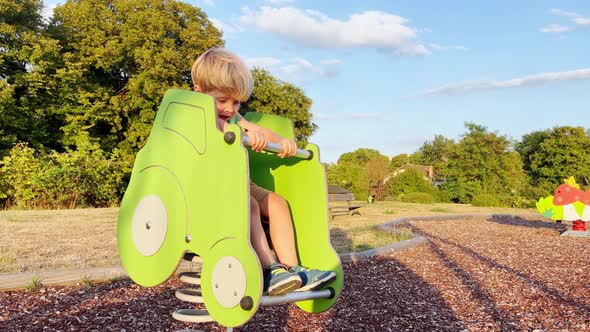 Little Boy Ride a Tractor Swings on Springs at Playground alt