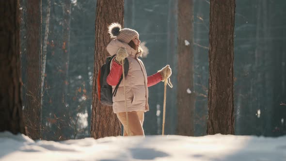 Young Woman Skier Looks with Admiration at the Snowy Forest alt