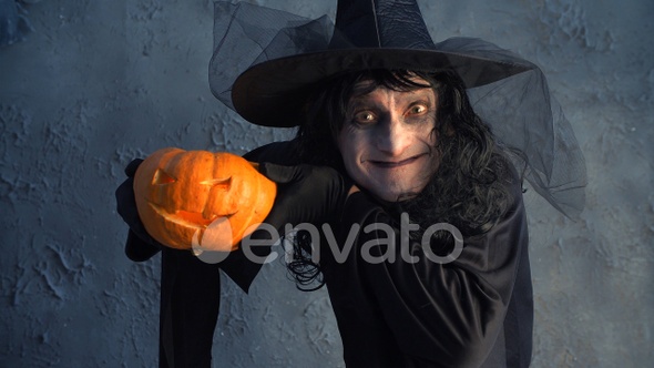 funny scary Halloween witch holding a pumpkin