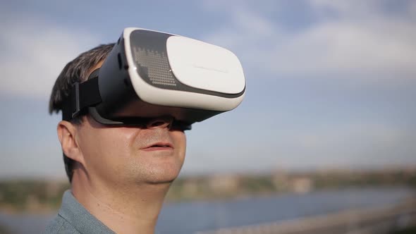 Man Uses a Virtual Reality Glasses on the Background of Blue Sky