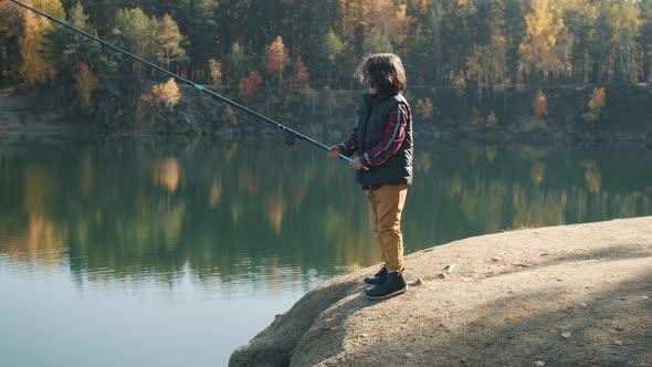 Portrait of Child Fishing in Lake Holding Rod on Sunny Autumn Day alt