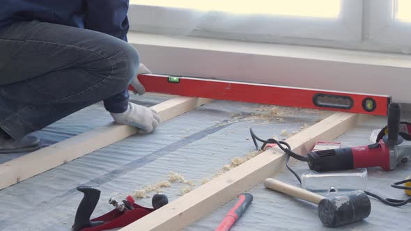 Master Carpenter Mounts Pine Wood Floor - Eco-friendly Flooring. Screwing Lag To Concrete.