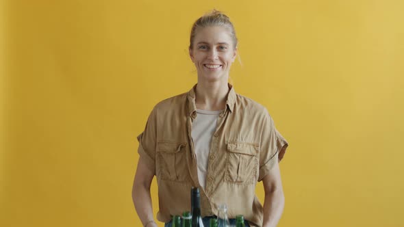 Portrait of Eco Activist Holding Box of Glass Bottles with Recycling Symbol alt